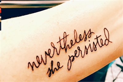 [ai] A tattoo on a person's forearm displaying the phrase 'nevertheless she persisted' in cursive font.